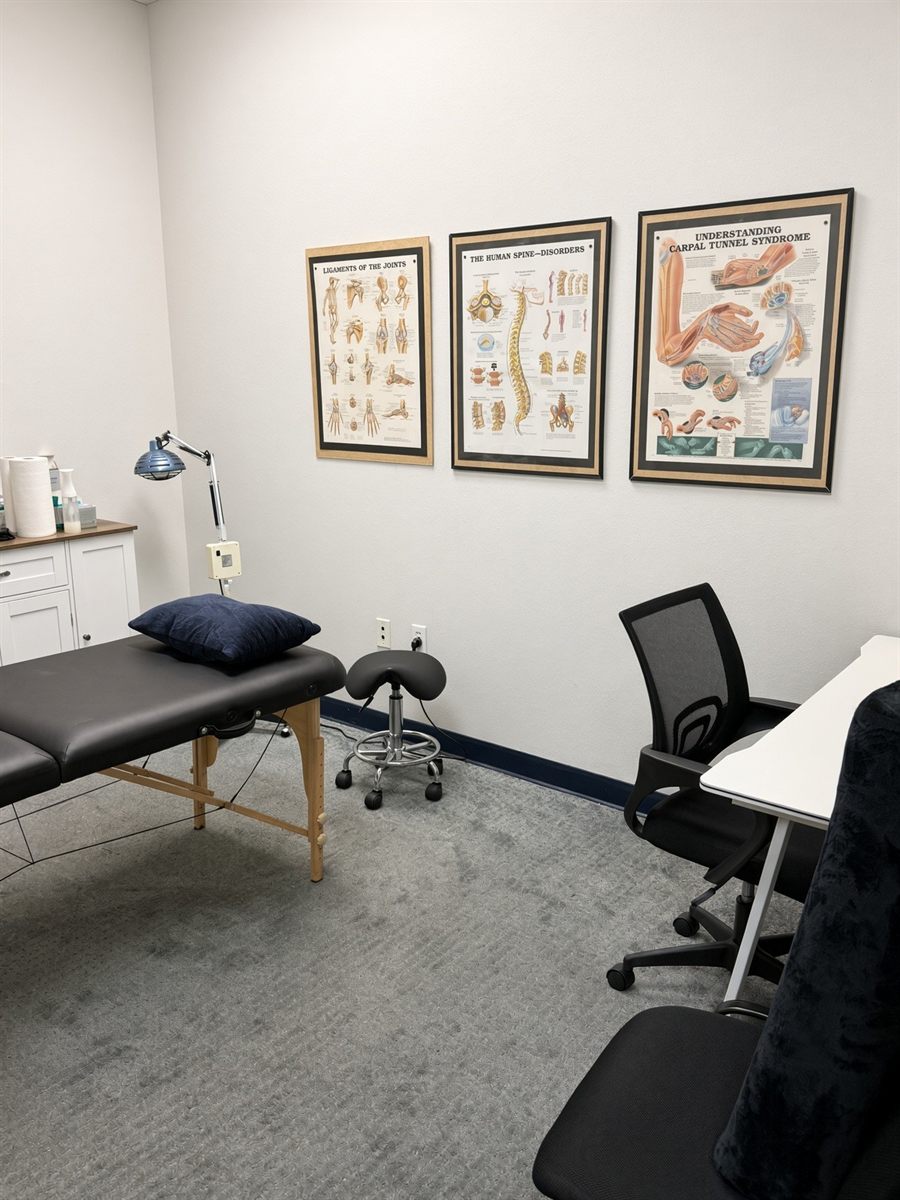 Private treatment room with table, heat lamp and anatomy charts